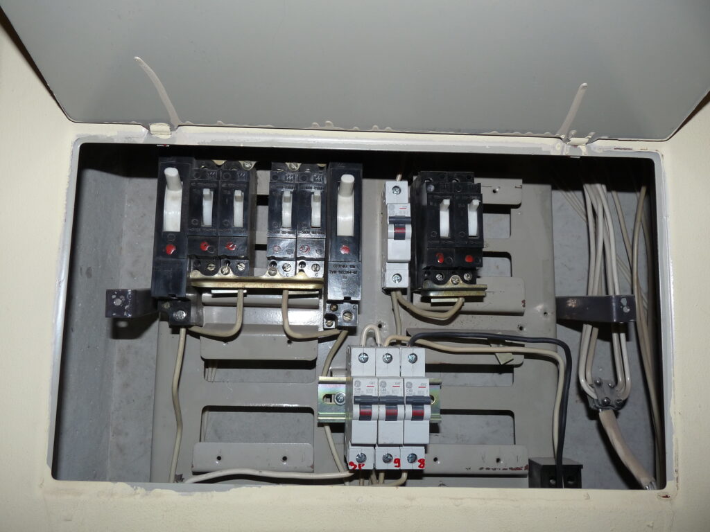 An open electrical panel with multiple circuit breakers and wires.