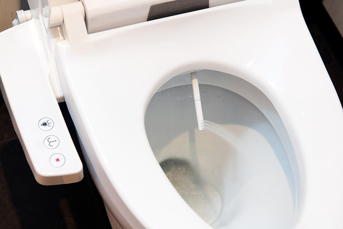 A sleek, modern white bidet toilet with an open lid and a convenient integrated control panel on the left side.