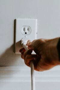 A hand expertly plugging a white electrical cord into a white wall outlet, showcasing the precision of a Vancouver electrician.