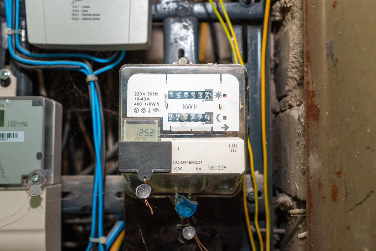 A close-up of an electricity meter displaying a reading of 15833.6 kWh - analog meter