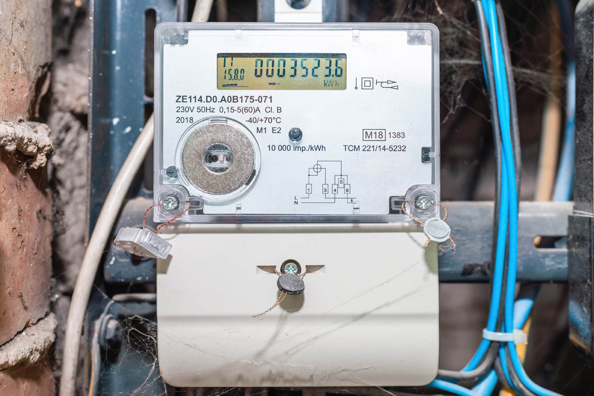 Close-up of an electricity meter showing a reading of 00035236 kWh. The device, which you can use to learn how to read your electric meter, is mounted on a wall and connected to blue and brown electrical wires.